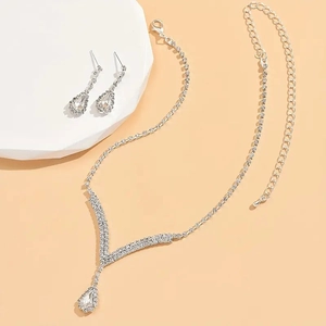 Détail de parure bijoux de mariée avec collier en V et boucles d'oreilles pendantes en strass