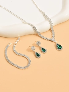 Detailed close-up of emerald pear-shaped necklace and earrings set with white diamonds
