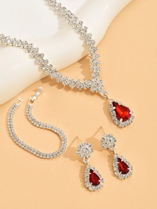 Detail of bridal jewelry set with red pear-cut stones and crystal-studded metal plating