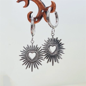Detailed view of silver heart earrings with sunburst spikes on a display stand