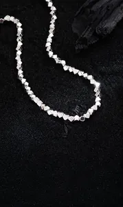 Macro shot of silver plated cube bead necklace on textured black stone background