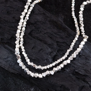 Minimalist silver cube bead necklace with geometric facets on a dark textured background