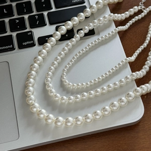 Collier de perles minimaliste français en trois tailles sur un bureau moderne
