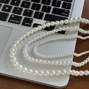 Colliers de perles de style français en quatre tailles présentés sur un bureau en bois
