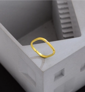 Detail eines quadratischen Goldrings mit weißem Diamant auf grauem Betonständer