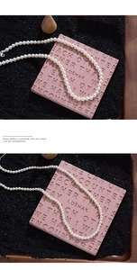 Detailaufnahme einer eleganten weißen Perlenkette auf rosa und schwarzem Hintergrund