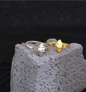 Makroaufnahme von gold- und silbernen Croissant-Ringen auf strukturiertem Steinboden