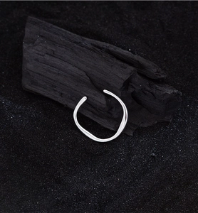 Macro di anello argento a onde irregolari con superficie lucida su sfondo carboncino