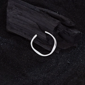 Anello aperto irregolare in argento con design ondulato su sfondo nero a contrasto