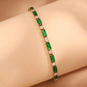 Détail d'un bracelet doré orné de gemmes vertes rectangulaires et de zircons brillants