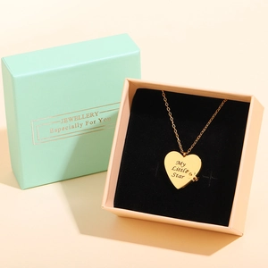 Macro shot of gold heart necklace with engraving in a luxury pink jewelry gift box