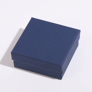 Vue macro d'un coffret cadeau bijoux carré bleu foncé avec texture mate et ombre portée