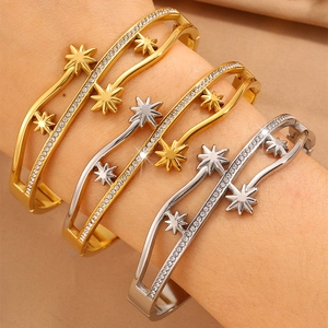 Détail de trois bracelets étoiles ou et argent sertis de zircons sur tissu plissé