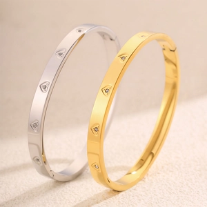 Dettaglio di bracciali in oro e argento con ciondoli a cuore e cristalli incastonati
