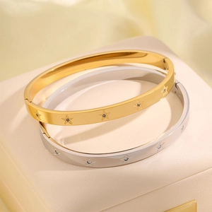 Dettaglio dei bracciali rigidi in acciaio inossidabile oro e argento con stelle incise