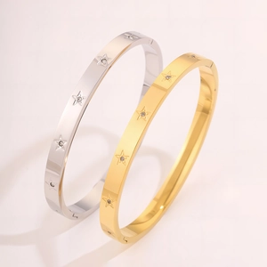 Dettaglio di bracciali in acciaio oro e argento con stelle e zirconi incastonati