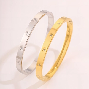 Dettaglio dei bracciali in acciaio al titanio lucido con motivi a cuore e pietre di zircone