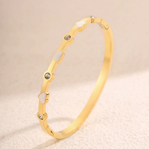 Dettaglio del bracciale dorato con cuori in smalto bianco e zirconi cubici tondi