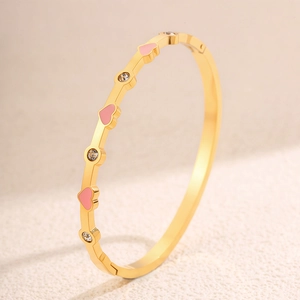 Dettaglio del bracciale placcato oro con cuori in smalto rosa e cristalli su pietra