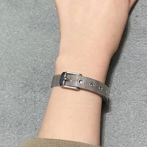 Détail macro du bracelet à maille milanaise argentée avec boucle réglable au poignet