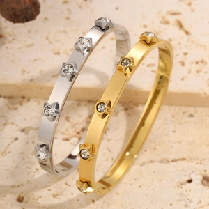 Macro detail of gold and silver stainless steel bangles with star-shaped zircon accents