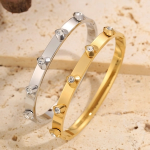 Macro detail of gold and silver heart-shaped bangles with crystals on stone background