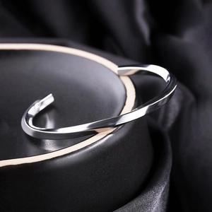 Macro shot of polished silver Mobius twisted cuff bracelet on luxury dark fabric
