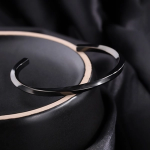 Macro view of polished black stainless steel Mobius open cuff bracelet on dark base
