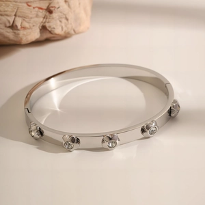 Detail of silver stainless steel bangle featuring floral charms and sparkling zircons