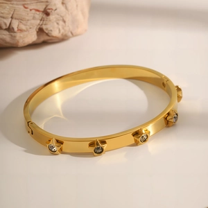 Detail shot of golden star bangle with sparkling zircons on a textured rock base