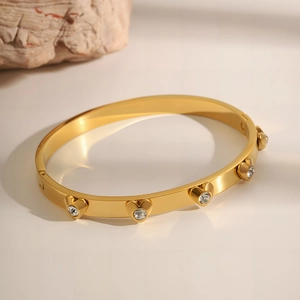 Detailed close-up of a gold heart bangle featuring polished finish and sparkling zircon stones