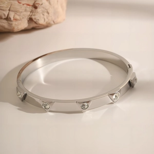Macro detail of silver stainless steel open bangle with triangle studs and inlaid crystals
