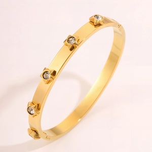 Macro detail of golden stainless steel bangle featuring star charms with zircon inlay