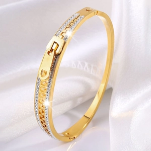 Macro view of gold-plated zipper bangle with sparkling pavé rhinestones on velvet