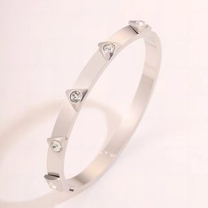 Macro detail of silver stainless steel bangle featuring triangle settings with clear crystals