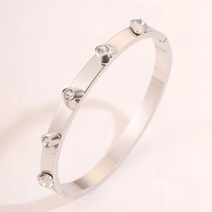 Macro detail of silver titanium steel bangle with five heart-shaped inset crystals