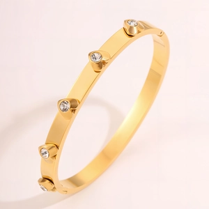 Detailed macro view of gold-plated stainless steel bangle with five heart-shaped zircons