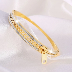 Macro shot of gold zipper design bangle with sparkling pave-set stones on silk