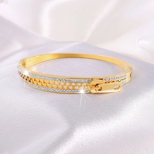Detailed macro view of gold zipper bangle featuring sparkling pave set crystals on white silk