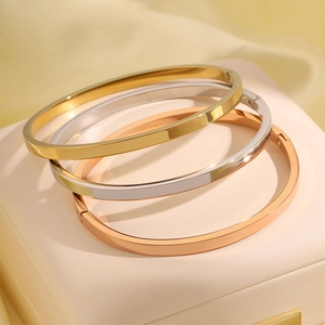 Gepolijste titanium stalen armbanden in goud, zilver en roségoud op een sieradendoosje
