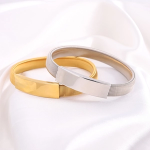 Dettaglio macro di bracciali in acciaio inossidabile oro e argento su seta bianca