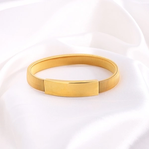 Dettaglio macro del bracciale in acciaio titanio dorato con trama a molla intrecciata