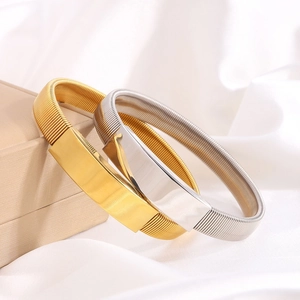 Bracciali in acciaio al titanio argento e oro lucido su elegante sfondo di seta
