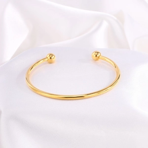 Brazalete abierto de acero inoxidable bañado en oro 18k con extremos esféricos en seda