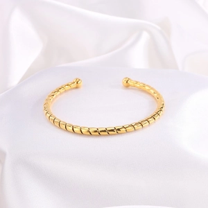 Primer plano detallado del brazalete de acero chapado en oro 18k con textura espiral