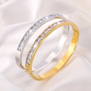 Dettaglio di bracciali in titanio oro e argento con zirconi cubici dal taglio princess