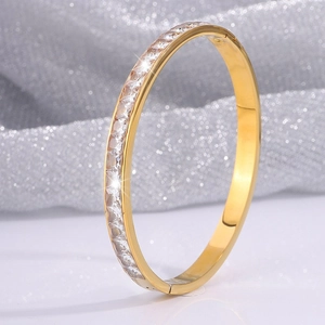 Dettaglio del bracciale in acciaio al titanio dorato con cristalli pavé e finitura lucida
