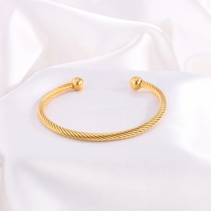 Primer plano de la pulsera abierta de cable trenzado chapado en oro con bolas de metal