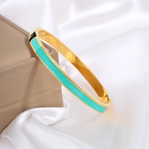 Detail van vergulde titaniumstalen armband met muntgroen email op zijden ondergrond