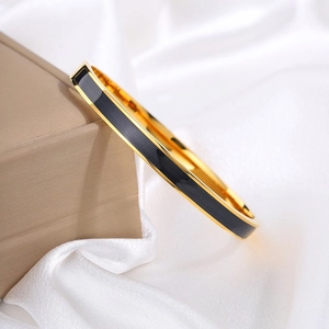 Detail van 18k vergulde titaniumstalen armband met zwart emaille inleg op zijde